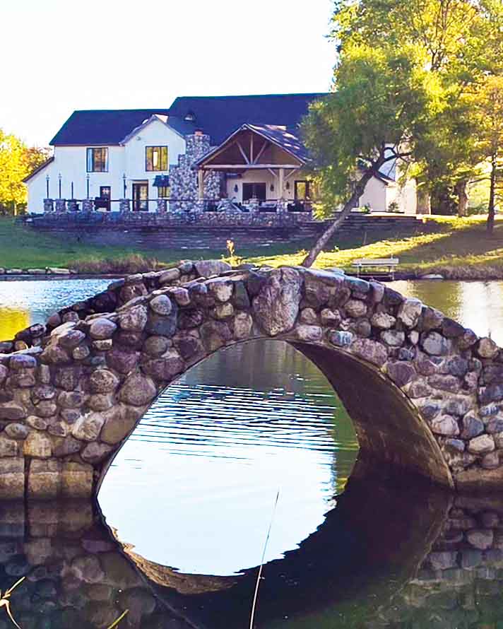 Stone Bridge Farm - Main house with pond and stone bridge in the foreground.